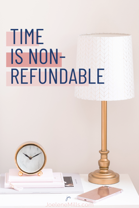 photo of a clock on a bedside table with a lap, notebooks and a pink phone. The words "time is non-refundable" 