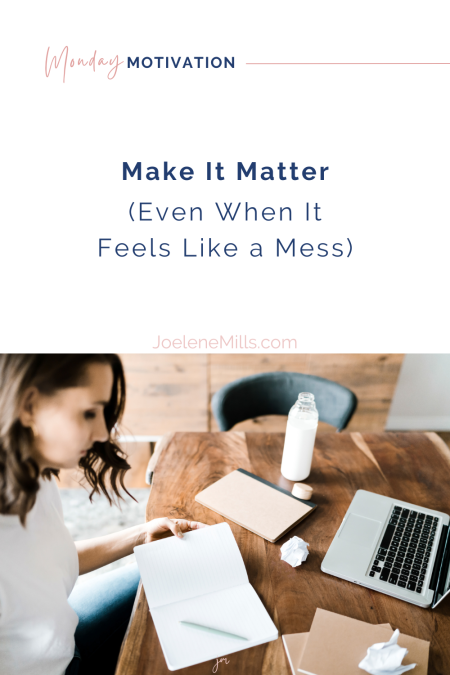 Woman journaling at desk with laptop, notebooks, and crumpled paper—reflecting on business clarity and how to make it matter in the messy middle.