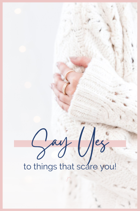 Woman wearing a white sweater, close up of her arm hugging herself with the words "Say yes to things that scare you" written over top